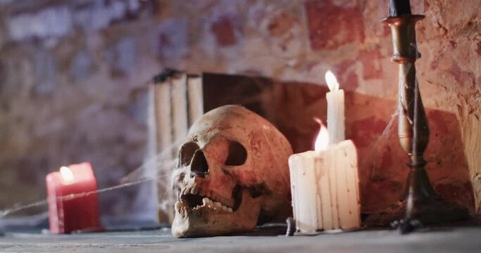 Video of stack of books with spider web, skull and candles on brick wall background