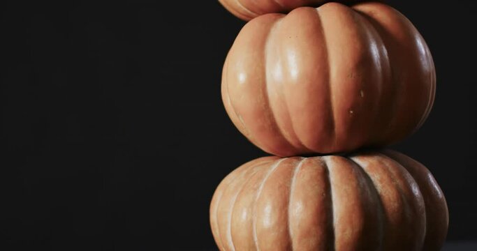 Video of stack of pumpkins on black background