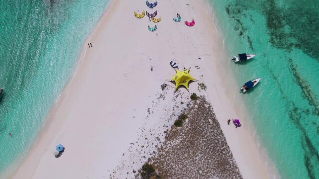 Drone descends tilting up to reveal sandy isthmus and kite surfing camp, cayo de agua