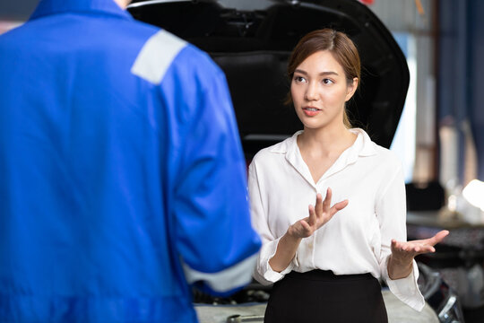 Woman Customer Meeting Mechanic And Talking About How To Fix A Car In Automobile Repair Shop