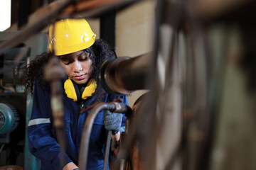 Technician engineer or worker woman in protective uniform with safety hardhat maintenance operation or checking lathe metal machine at heavy industry manufacturing factory. Metalworking concept