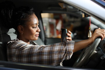 Portrait of happy woman with smiling face driving car vehicle while using smart mobile phone on the...