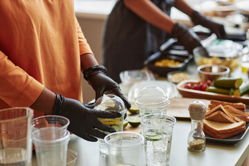 Closeup of woman wearing gloves making refreshing lemonade drinks in plastic cups for food delivery, copy space