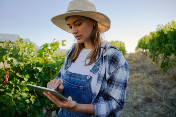 Young caucasian women in casual clothing using digital tablet next to plants on farm
