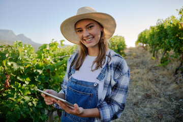 Happy young caucasian women in casual clothing holding digital tablet next to plants on farm