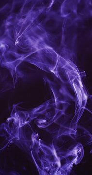 Vertical video of purple clouds of smoke moving with copy space on black background