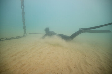 Anonymous diver with harpoon hunting in deep sea