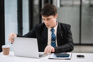 Business man working at office with laptop and documents on desk, financial adviser analyzing data.