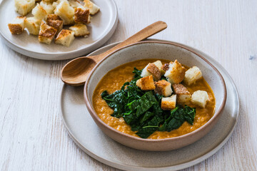 Healthy curry creamy soup with seasonal summer vegetables, sunflower seeds,  croutons, healthy vegan meal in rustic bowl