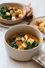 Healthy curry creamy soup with seasonal summer vegetables, sunflower seeds,  croutons, healthy vegan meal in rustic bowl