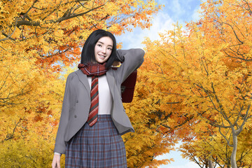 秋に紅葉が映える風景を背に通学する女子高生