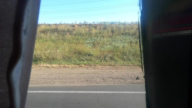 View from the bus window. View of the fields, trees, blue sky, the road through the curtains on the window of a moving bus. Concept relocation travel tourism transport transportation trip journey