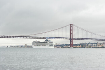 Huge cruise ship passes along the river under the bridge in cloudy weather