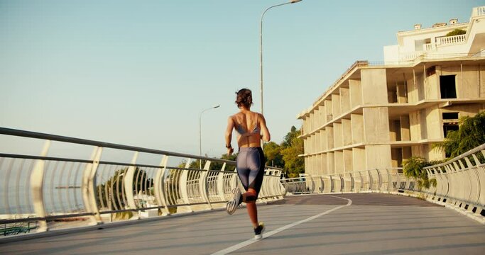 A girl in a sports summer uniform runs along the road and makes a twist on the corner. Morning jogging is the key to a healthy lifestyle