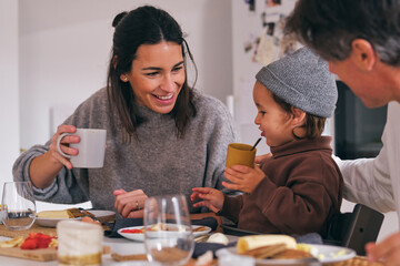 Crop cheerful family talking to girl during breakfast in house