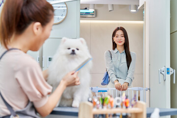 한국 포메라니안 강아지 애완견 애완동물 펫샵 미용실에서 미용을 하고 있는 미용사와 강아지를 기쁘게 바라보고 있는 강아지 견주 고객 손님 모습 © Asian Portrait Image