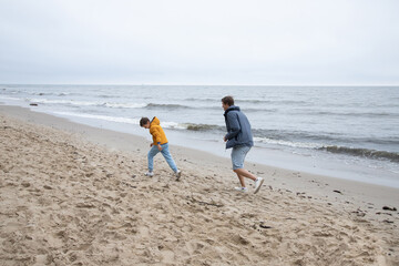 Father and son play and run on the autumn beach. cool autumn weather.