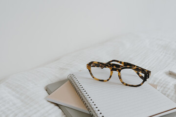 Notebook sheets, glasses, tablet on white muslin cloth. Artist home office workspace