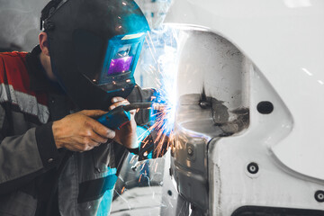 Body shop worker welding car body. Work with carbon dioxide weld. - obrazy, fototapety, plakaty