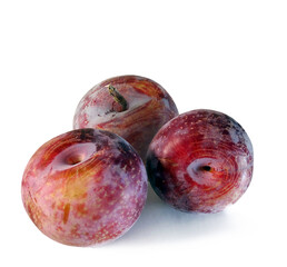 Three fresh ripe purple plums close up isolated on white background