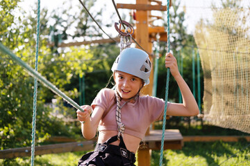 Little Girl Having Fun in a Rope Park Trail Facility. Happy little child enjoying climbing in an...