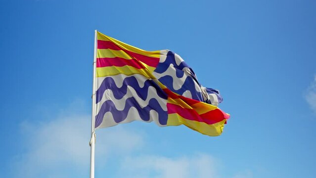 A vibrant flag fluttering in the sunny breeze of Barcelona