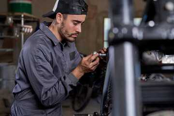 Focused ethnic technician repairing motorcycle in workshop