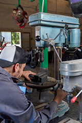 Male mechanic using drilling machine in workshop