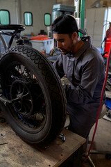 Concentrated male mechanic fixing motorbike wheel