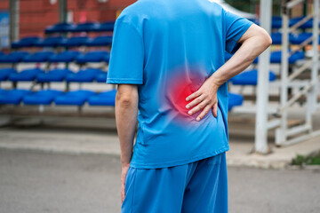 Back pain, kidney inflammation, man suffering from backache on a sports ground after workout