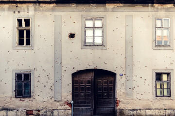 Residental building facade heavily damaged in the Balkans war. Window with bullet hole on war.