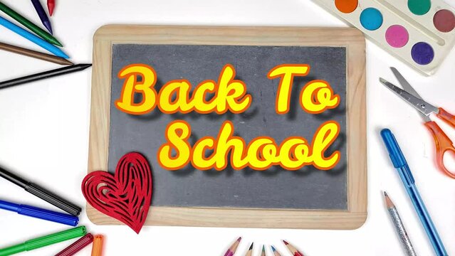 Back to school illustration on blackboard, view of a red heart. Crayons, ruler, tempera and stationery for school.