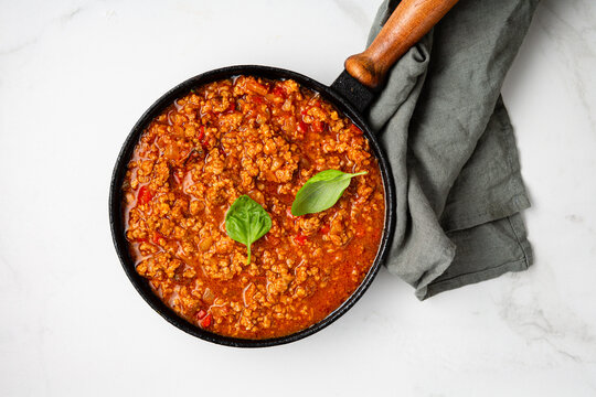 Meat tomato sauce in pan bolognese on marble surface food top view