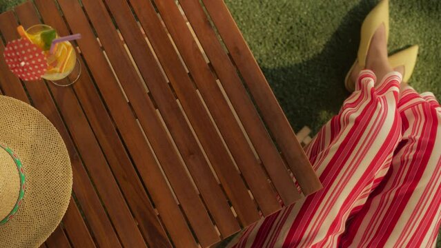 Top Down View on an Empty Garden Table with an Elegant Anonymous Female in a Cafe. Tabletop with a Refreshing Cocktail and Straw Hat. Background for Text for Travelling, Vacation and Summer Offers
