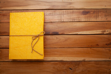 Beautiful yellow Diary made with handmade paper, on a wooden background. Top view.
