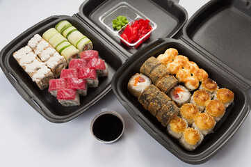 a set of sushi rolls in dark boxes. concept: food delivery