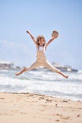 Obraz premium Carefree boy jumping on sandy beach