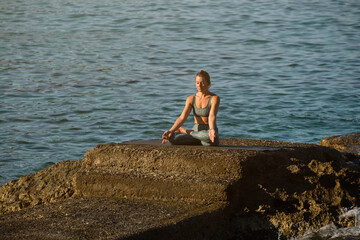 Calm woman meditating on stone at seaside