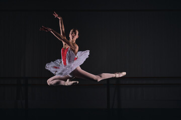 Flexible woman ballerina jumping while dancing ballet role