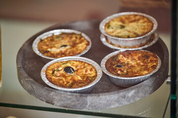 Small vegetarian quiche with olive and cheese on stone plate