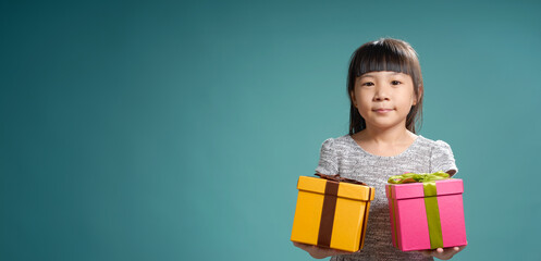 Portrait of little asian girls holding two birthday presents ,  isolated on light green background .