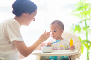 Baby eating solid foods in high chair.