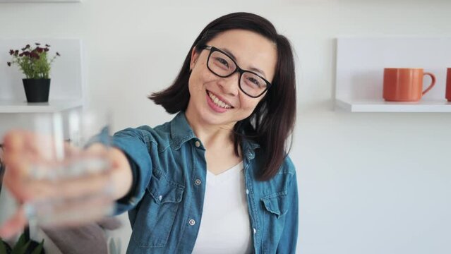Slim female holding beverage in hand on kitchen background