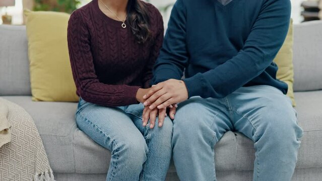 Love, hope and couple on a sofa holding hands in support of mental health, criss and empathy in their home. Depression, trust and people in living room for comfort, sorry and kindness for infertility