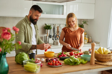 Affectionate couple cutting vegetable in the kitchen