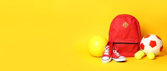 Balls, backpack and sneakers on yellow background