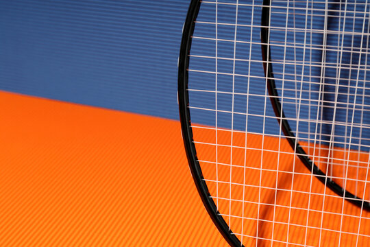 Badminton rackets on orange and blue textured backgrounds