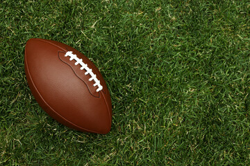 American football ball on green grass background
