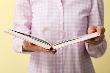 Open book in female hands on yellow background