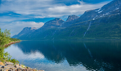 Fototapeta na wymiar Beautiful rocky hill with waterfall above sea fjord